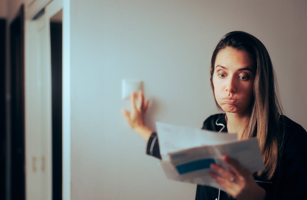 Woman,Checking,Electricity,Bill,Turning,Out,The,Lights,At,Home.